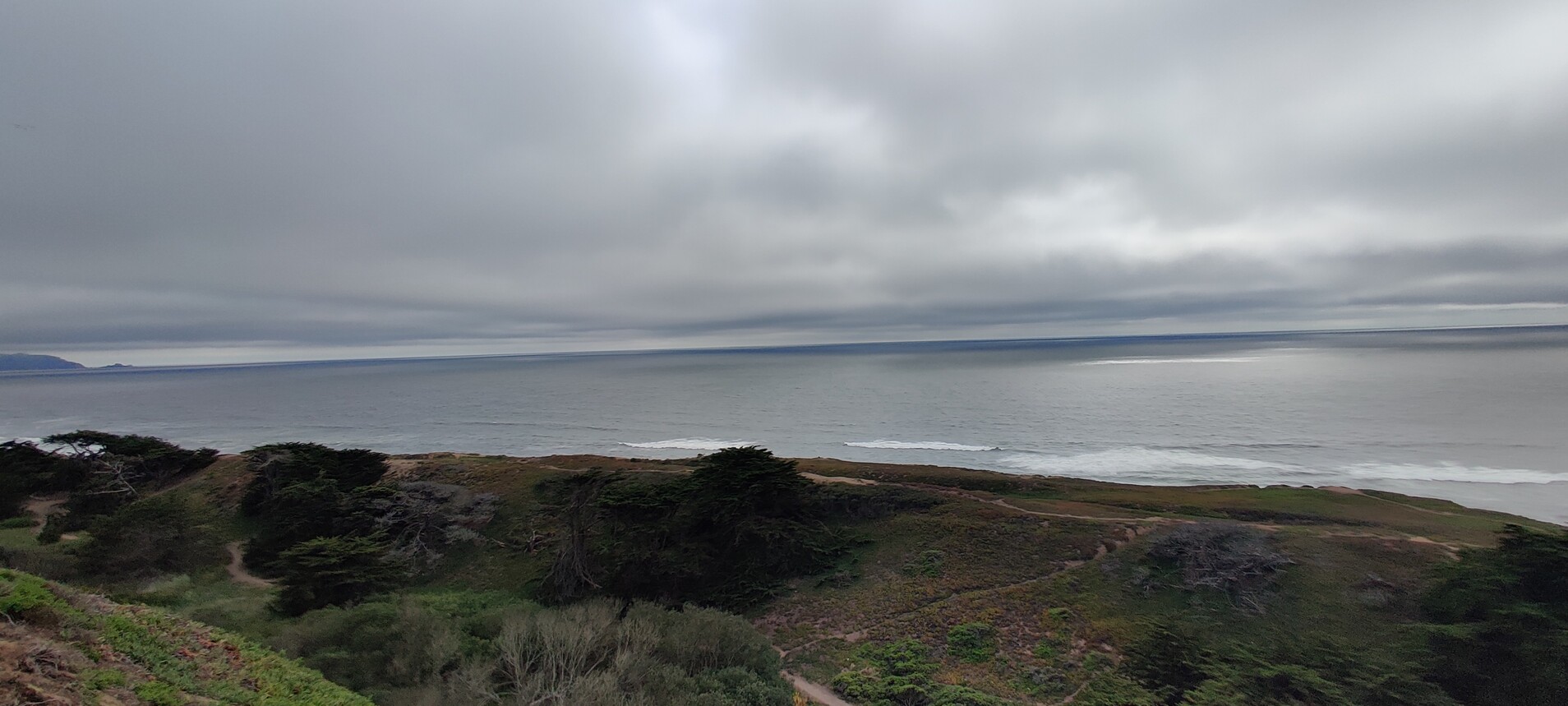 View from cliffs right alongside the California coastline on an overcast/cloudy day.