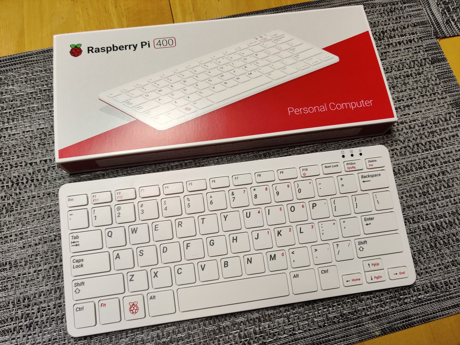 A Raspberry Pi 400 Personal Computer keyboard next to the box it came in.