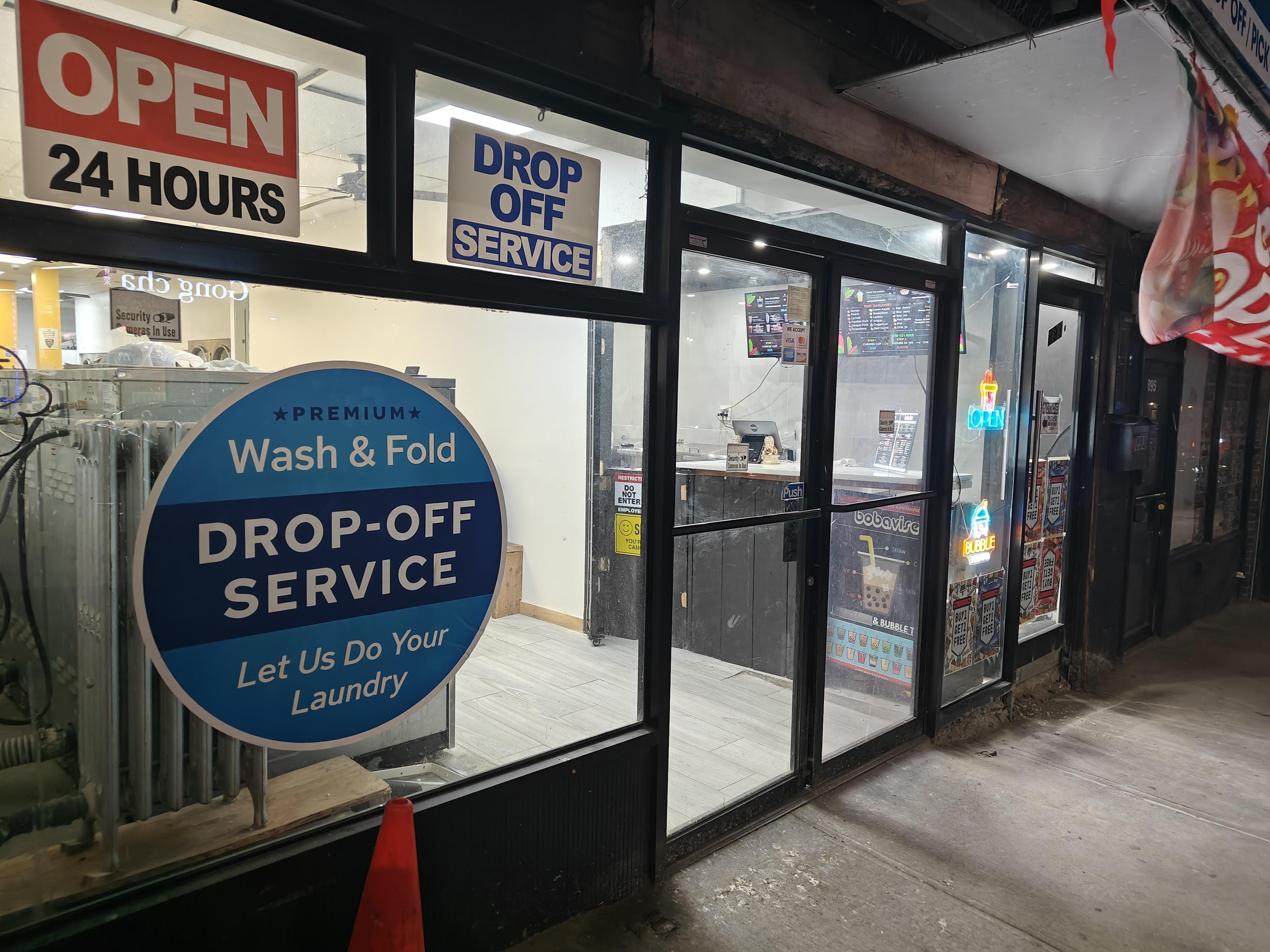 Exterior of a laundromat, through the doors/glass you can see a the counter of a boba shop on the right.