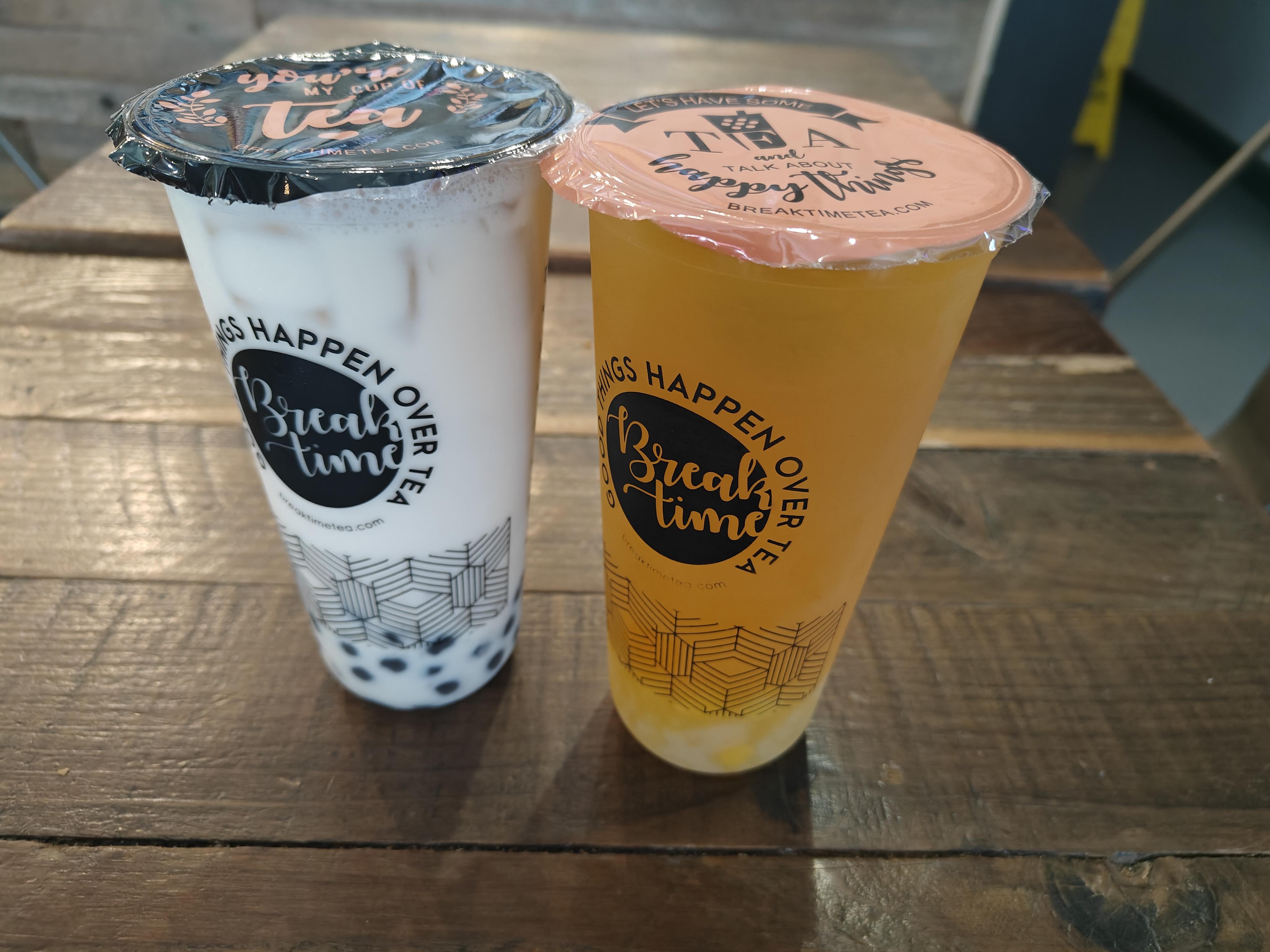 Two boba drinks, one on the left is a green milk tea, and on the right is a orange-ish clear drink