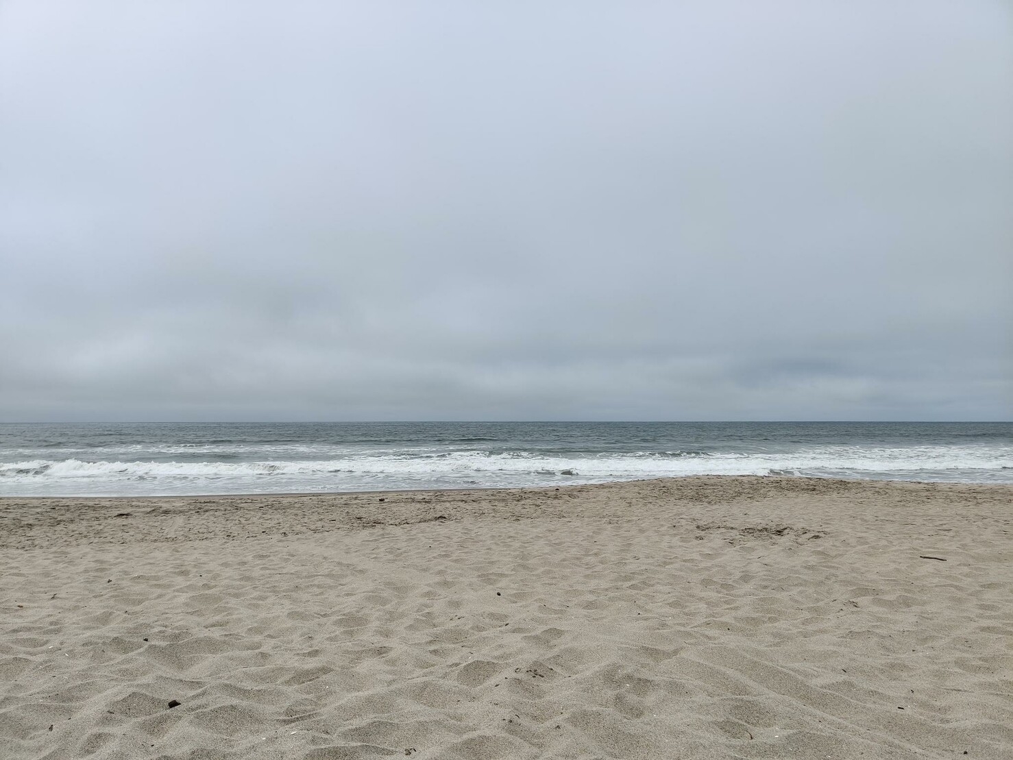 Overcast sky, bit of Pacific Ocean and a empty beach