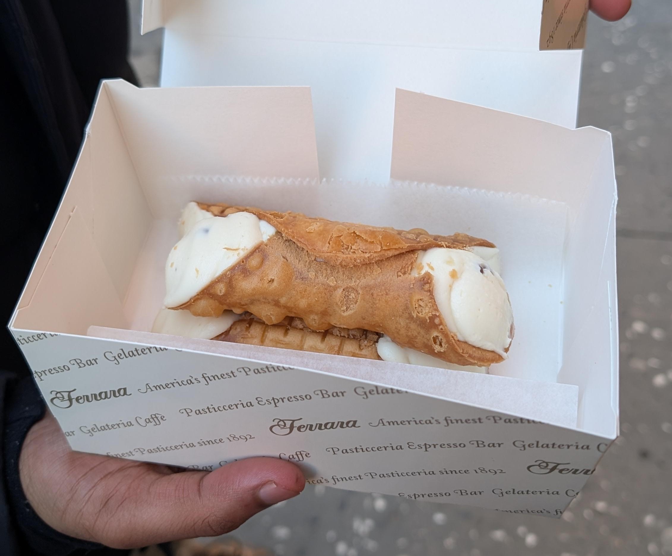 Three cannoli stacked in an open box