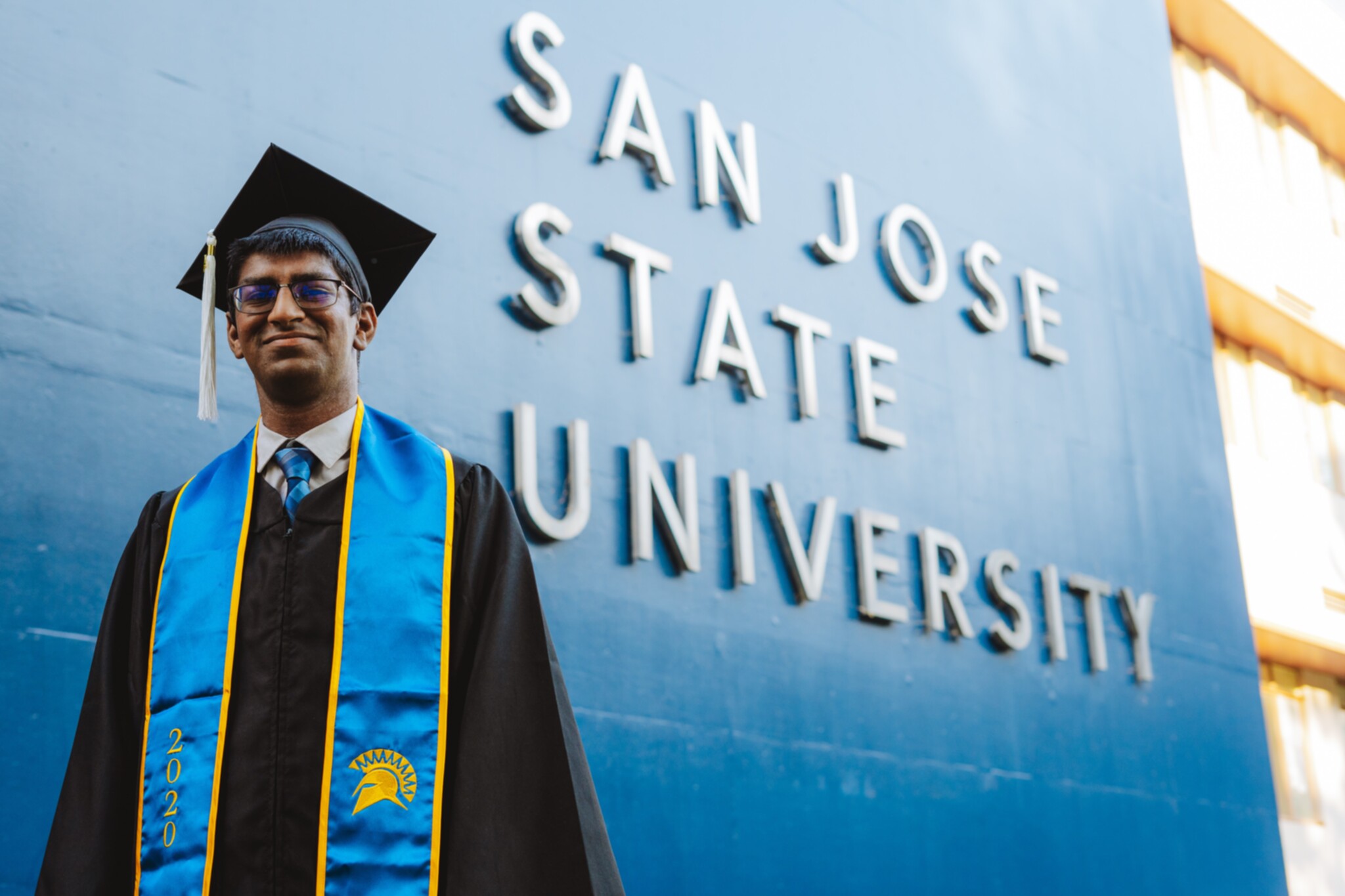 Me, wearing my cap and gown, in front of the San Jose State University sign