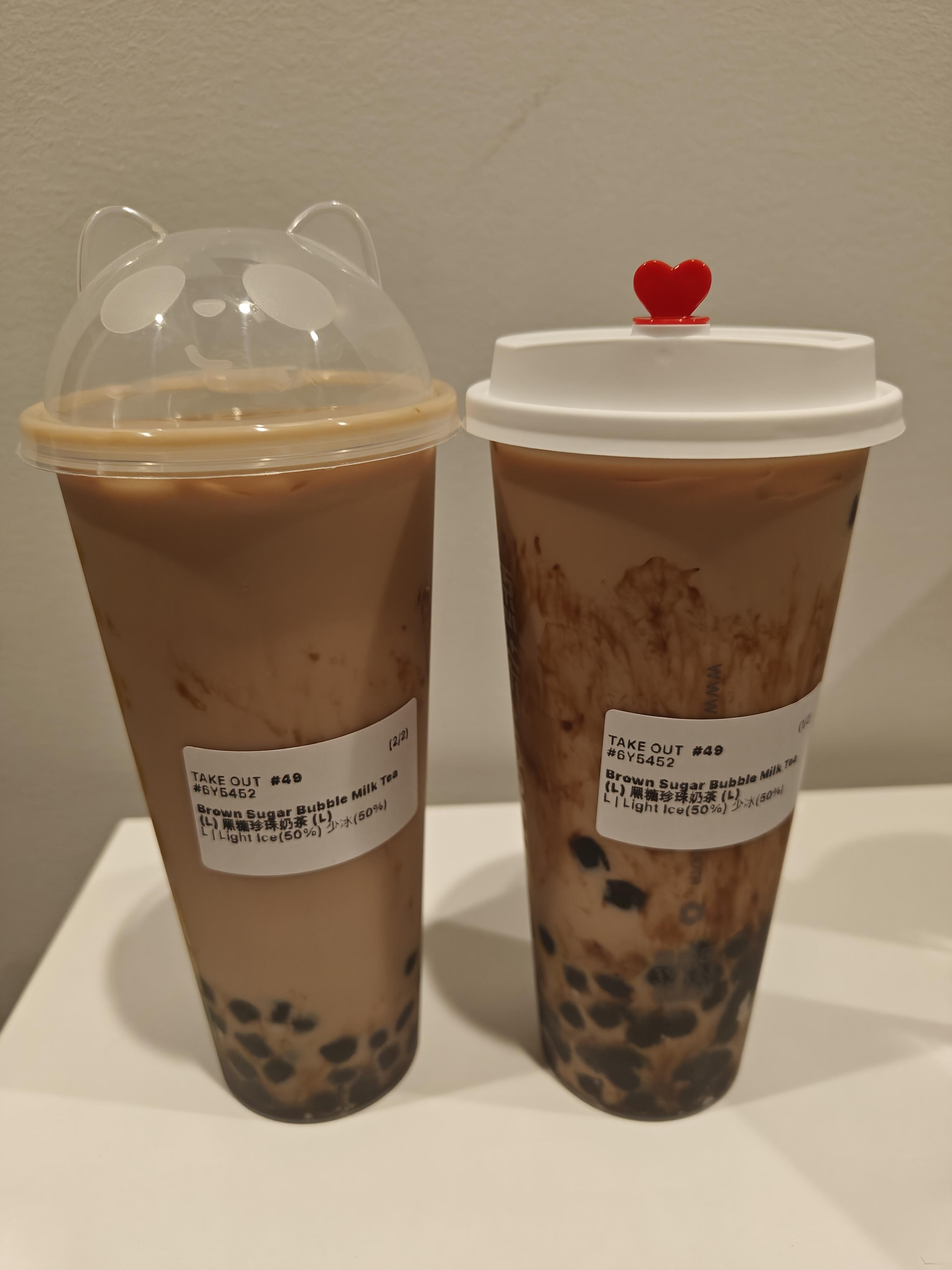 Two cups of boba; the one on the left has a clear lid with cat ears and on the right has a small heart in the lid